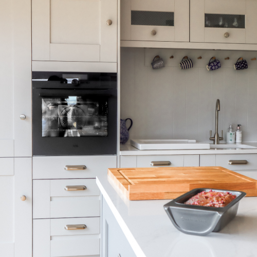 Laura Ashley Whitby Platinum Kitchen with wooden Laura Ashley chopping board and a tin with Lemon and Rose drizzle cake 